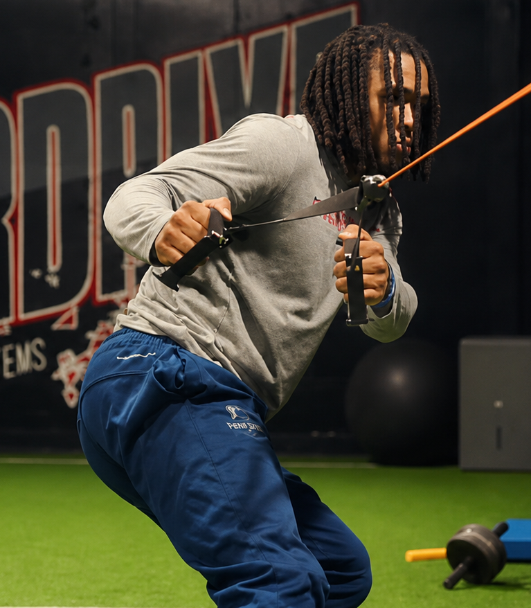 Overdrive athlete training with resistance band in front of the Overdrive Elite Performance Systems wall logo